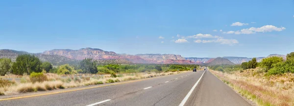 Panorama de estrada do deserto com montanhas vermelhas no horizonte — Fotografia de Stock