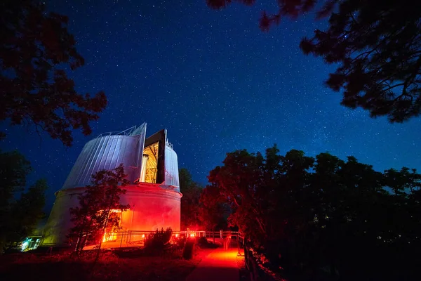 Krajina observatoře osvětlené v červených a modrých světlech v noci se stromy v pozadí — Stock fotografie
