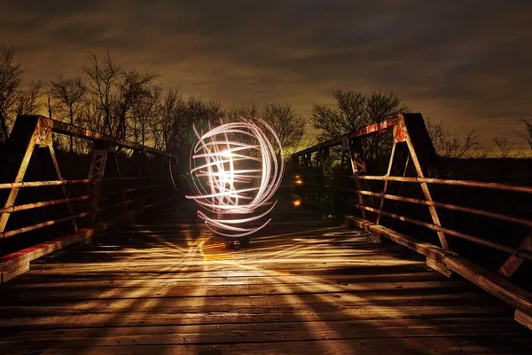 Zigzagging luz branca ilumina uma ponte de metal ao entardecer — Fotografia de Stock