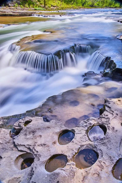 Costa rocciosa con piccoli fori accanto a piccole cascate a cascata — Foto Stock