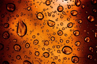 Kehribar rengi cam bir fonda su damlacıkları. Bira bardağına benziyor.