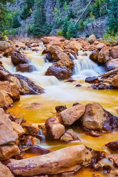 Червоні камені вздовж золотої річки з каскадними водоспадами — стокове фото