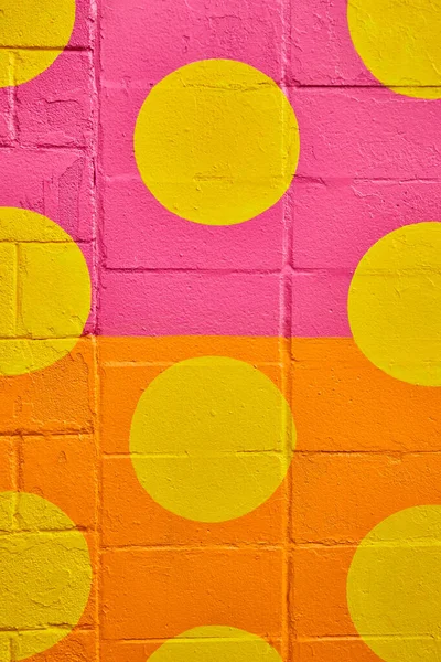 Függőleges cement fal közel osztva rózsaszín és narancssárga festék körök sárga — Stock Fotó