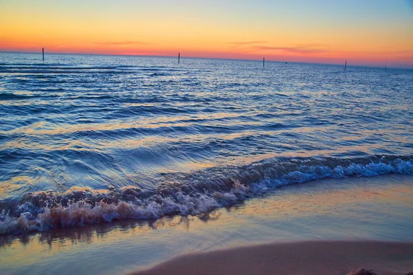 Plaża na jeziorze z falami wody i zachodu słońca kolory na horyzoncie — Zdjęcie stockowe