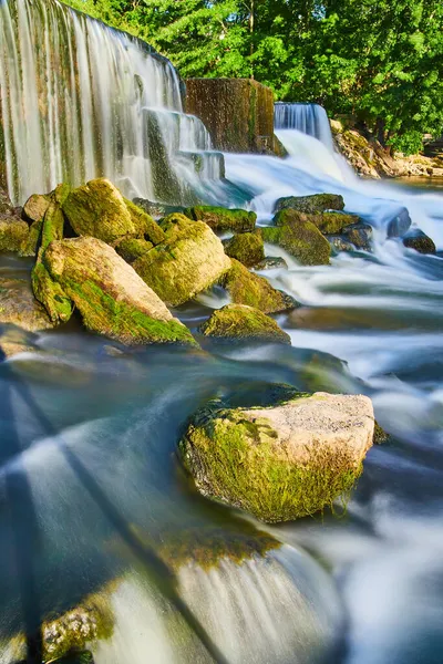 Algenrotsen naast door de mens gemaakte watervallen en glad water — Stockfoto