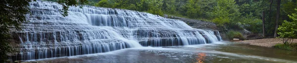 Panorama dużego kaskadowego wodospadu nad skałami w zielonym lesie — Zdjęcie stockowe