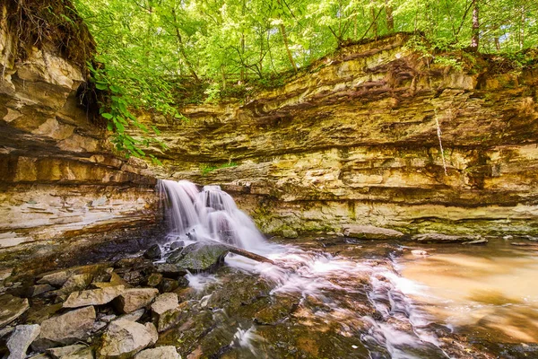 Bred utsikt över vattenfall stänk av stenar i kanjonen av grön skog — Stockfoto
