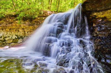 Beyaz şelalenin manzarası kayaların üzerine dökülüyor.