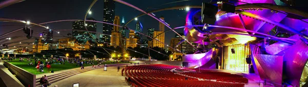 Panorama of outdoor theater in Chicago at night that shows the skyline and the auditorium lit up in purple and yellow lights — Stock Photo, Image