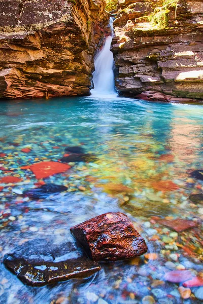 Kleurrijke rivier rots in focus met grote waterval en kliffen op de bodem van kloof — Stockfoto