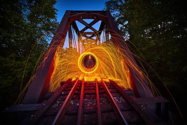 Steel wool sparks of orange at night on train track bridge — Stock Photo, Image