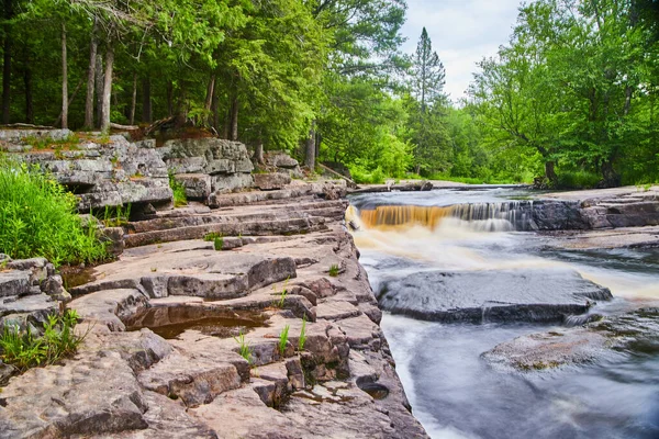 Vattenfall skapar liten ravin med nivåer av grå stenar i skogen — Stockfoto