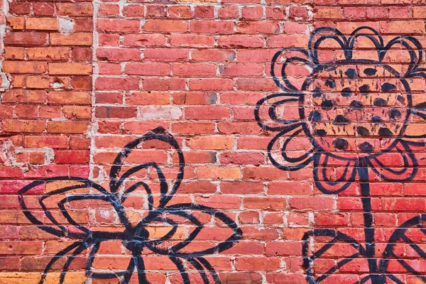 Red brick wall texture with simple black flower artwork — Stock Photo, Image