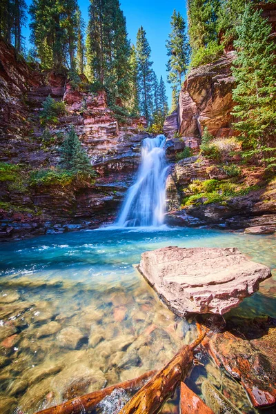 Canyon con cascata che si riversa dalle rocce nella baia di sole acqua blu con grande masso — Foto Stock