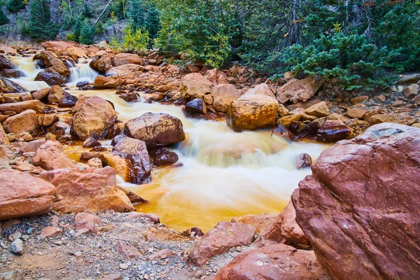Річка, вистелена великими червоними скелями і деталями каскадних водоспадів — стокове фото