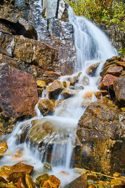 Крупним планом малий водоспад над червоними і коричневими каменями — стокове фото