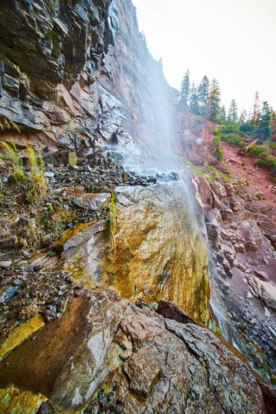 Vista dal lato di alta cascata che si schianta su scogliere rocciose colorate — Foto Stock