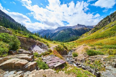 Büyük bir dağ sırasının vadisinde nehrin yanındaki çökmüş yapılar.
