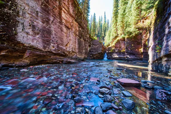 Низький вид на мілководдя, наповнене різнокольоровими скелями в каньйоні водоспадом — стокове фото