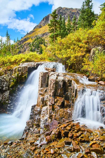 Cachoeiras sobre pedaços de rochas no início do outono com a montanha no fundo — Fotografia de Stock
