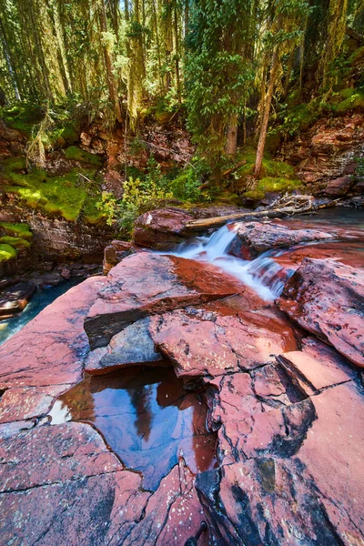 Червоні скелі з відрами води і дрібними водоспадами зі скелями мохоподібних скель на фоні — стокове фото