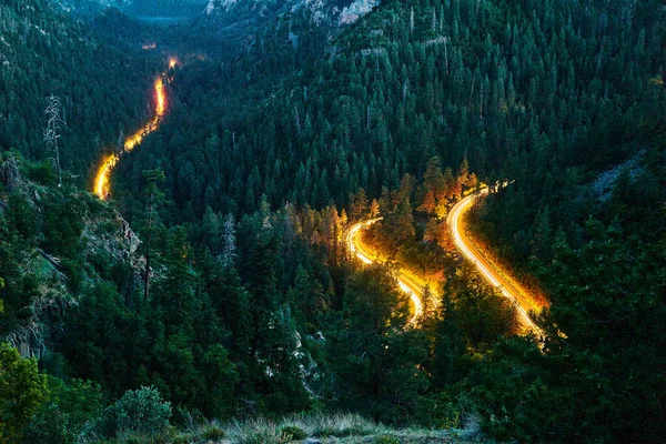 Winderige weg in de bergen met koplampen van auto 's rijden door — Stockfoto