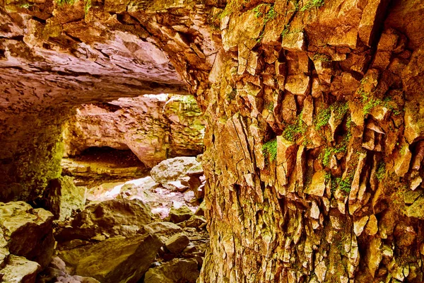 Cave pillar of chunks of rock covered in moss with cave opening in background — Stock Photo, Image