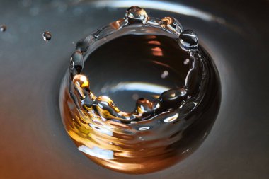 Üzerinde siyah, altın ve beyaz bir su damlası olan bir taç.