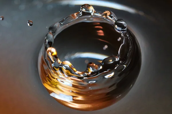 Kron av vatten med en vattendroppe som har svart, guld och vitt — Stockfoto