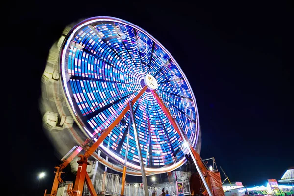 Rueda de la fortuna por la noche con luces azules y blancas en una feria o carnaval —  Fotos de Stock