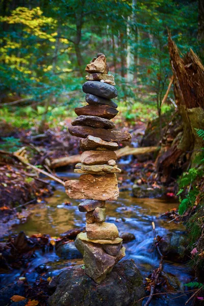 Cairn de rocha com um rio e uma árvore caída na floresta atrás dele — Fotografia de Stock