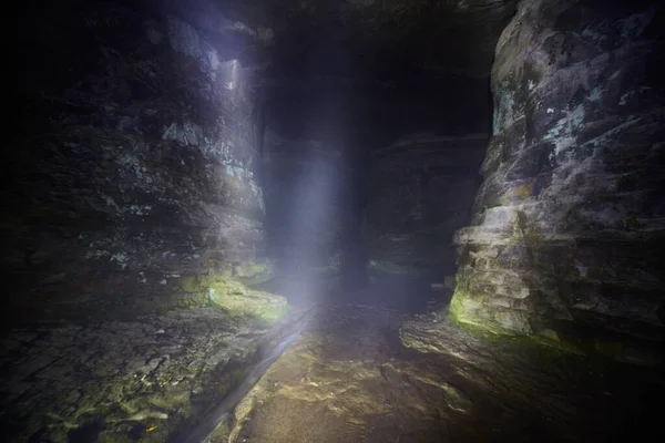 Eixo de luz em uma caverna grande com um riacho minúsculo que corre através dela — Fotografia de Stock