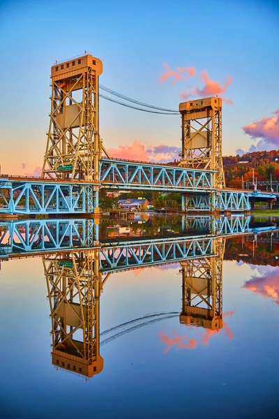 Houghton sunrise of soft blues and purple and pink clouds with glassy surface of river water and the lift bridge — Stock Photo, Image