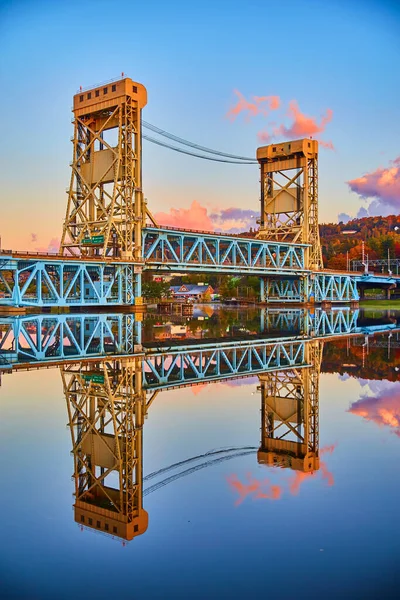 Houghton amanecer de blues suaves y nubes púrpura y rosa con superficie vidriosa de agua del río y el puente elevador — Foto de Stock