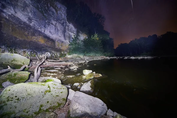 Banco rochoso de um rio à noite com um precipício e pinheiros e um céu crepúsculo — Fotografia de Stock