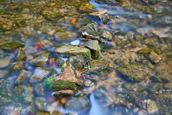 Kleine moosbewachsene Felsen in einem flachen Flussbett — Stockfoto