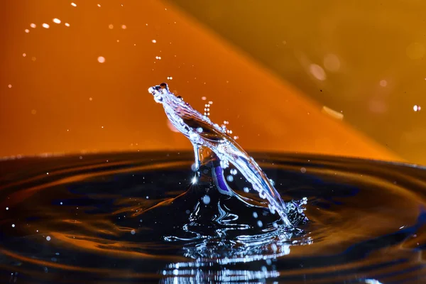 Slanted vízcsepp narancssárga háttérrel, amely úgy néz ki, mint egy csillagközi lövés — Stock Fotó