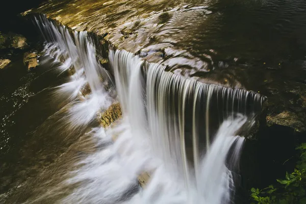 Close view at angle of edge of waterfalls flowing into river — Stock Photo, Image