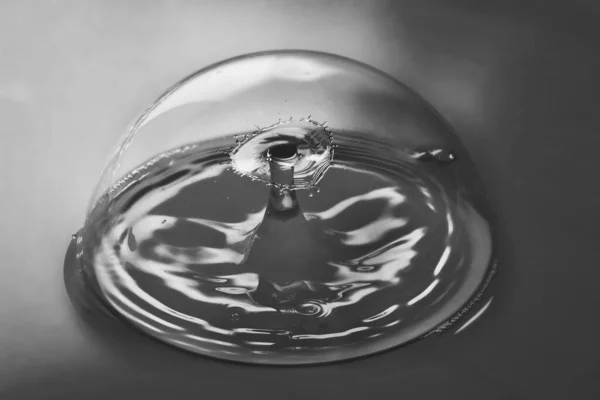 Schwarz und Weiß einer makellosen Blase, die Wellen von zwei Wassertropfen enthält, die in der Luft kollidieren — Stockfoto