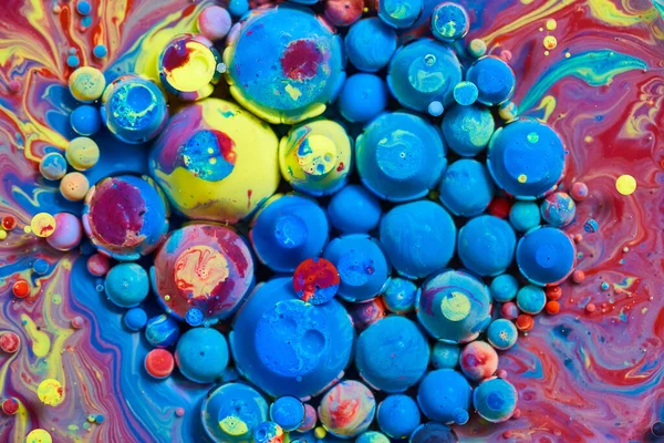 Cluster blauer und regenbogener Kugeln auf der Oberfläche bunter Flüssigkeit — Stockfoto