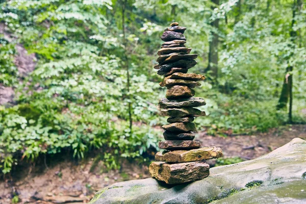 Wysoki stos kairn kamieni na wyciszonym zielonym tle lasu — Zdjęcie stockowe
