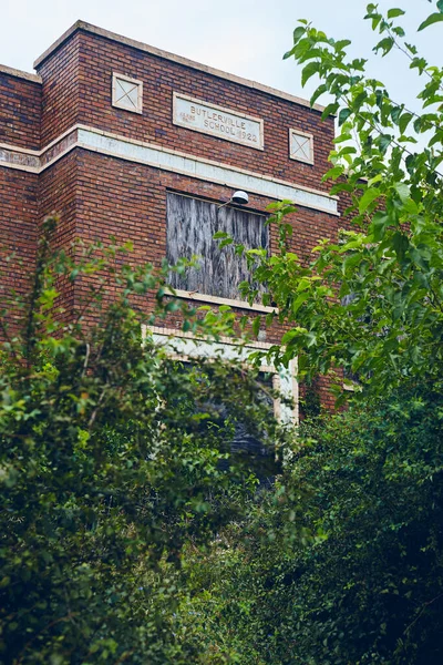 Roter Backstein verlassenes Schulgebäude umgeben von grünen Büschen — Stockfoto