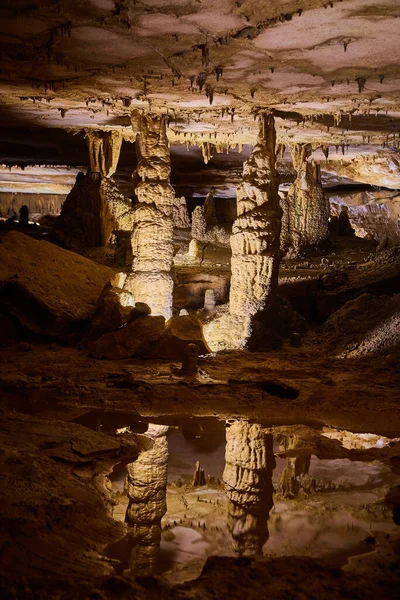 Majestoso par de estalagmites refletindo em água cristalina de caverna profunda — Fotografia de Stock