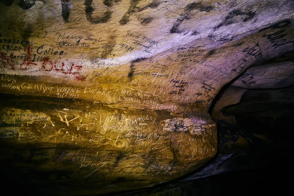 Імена, вирізані в печерну стіну в оточенні темряви — стокове фото