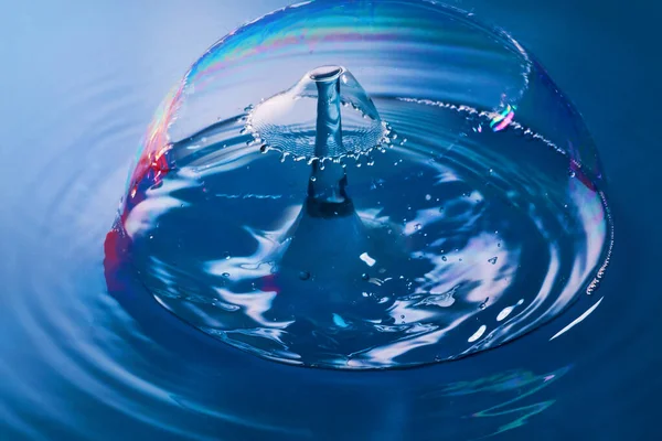 Békés kék víz buboréktöréssel, ahogy két vízcsepp összeütközik. — Stock Fotó