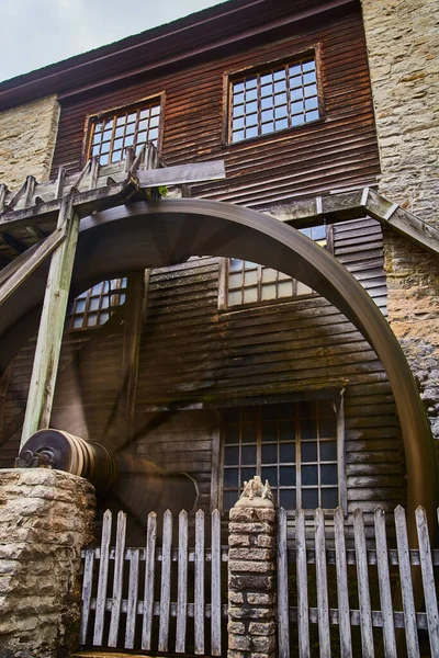 Колесо воды на старой мельнице с кирпичными стенами и деревянным забором — стоковое фото