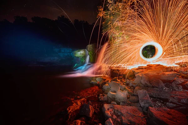 黄色い球体の火花を散らしながら夜に輝く滝 — ストック写真