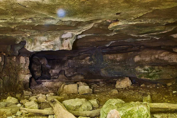 Nearly flat roofed cave with large rocks strewn across the ground — Stock Photo, Image