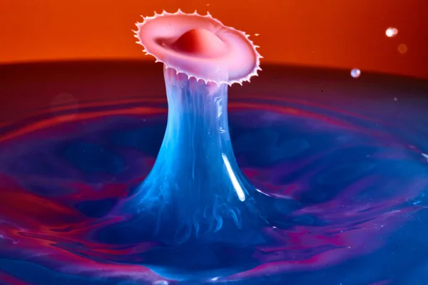Splash ομιχλώδες μπλε νερό με έκρηξη τύπου πριονιού και κόκκινο και μωβ φόντο — Φωτογραφία Αρχείου
