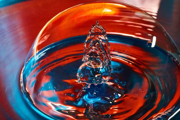 Água azul e vermelha com bolha grande e duas gotas de água colidindo dentro — Fotografia de Stock